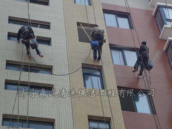 在樓頂架設(shè)吊籃將工人運送到指定位置進(jìn)行施工操作